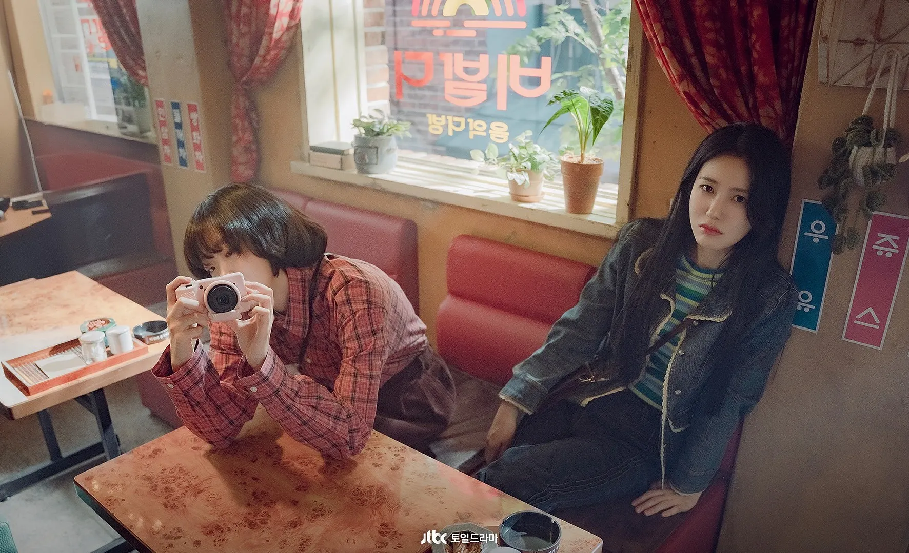 Cảnh phim Trăm Mảnh Ký Ức – Kim Da Mi và Shin Ye Eun trong quán cà phê hoài cổ thập niên 1980, thể hiện không khí thanh xuân Hàn Quốc.