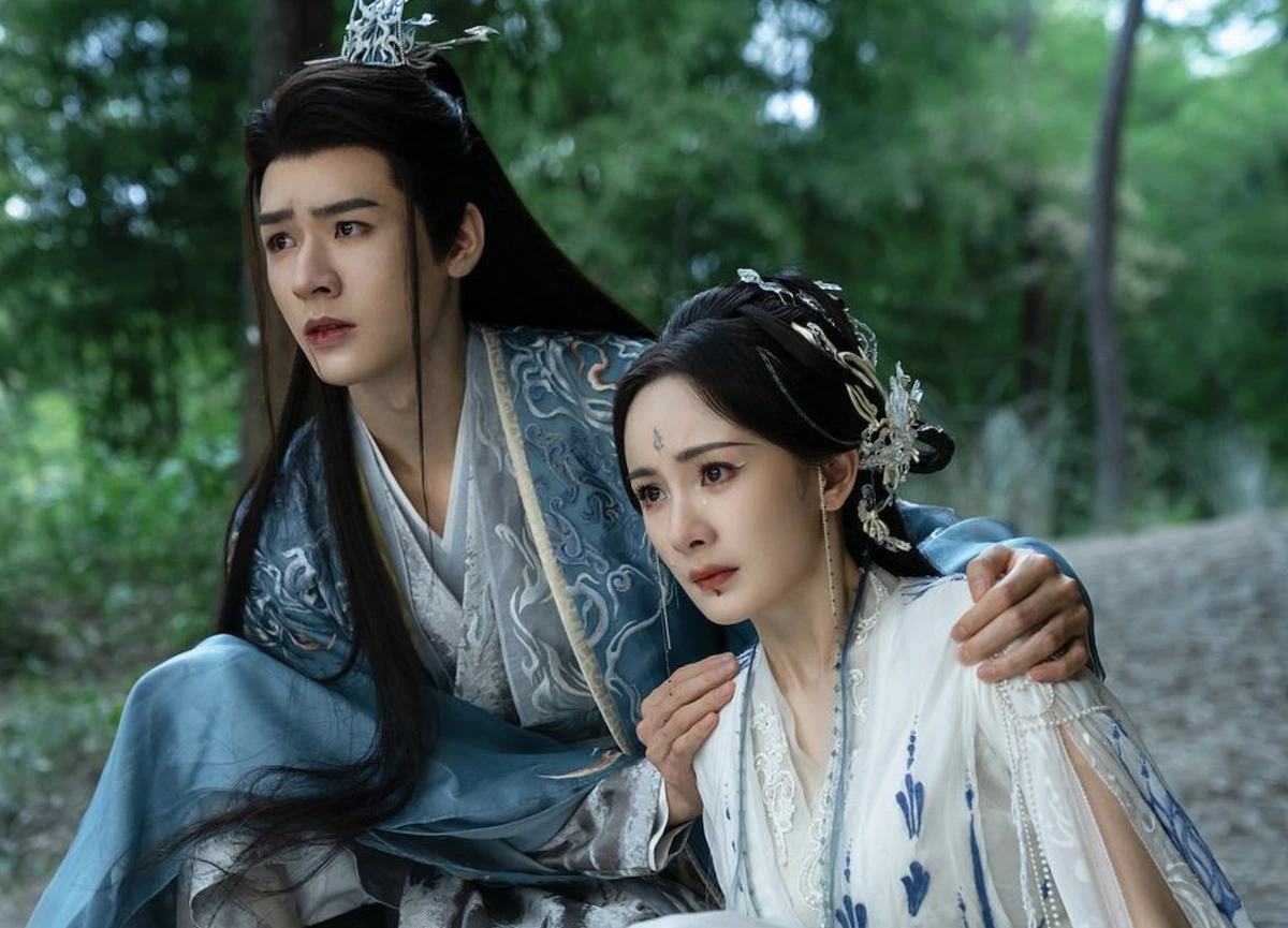 Cảnh phim Hồ Yêu Tiểu Hồng Nương – hai nhân vật chính ngồi bên nhau giữa rừng, thể hiện sự che chở và tình cảm sâu lắng.